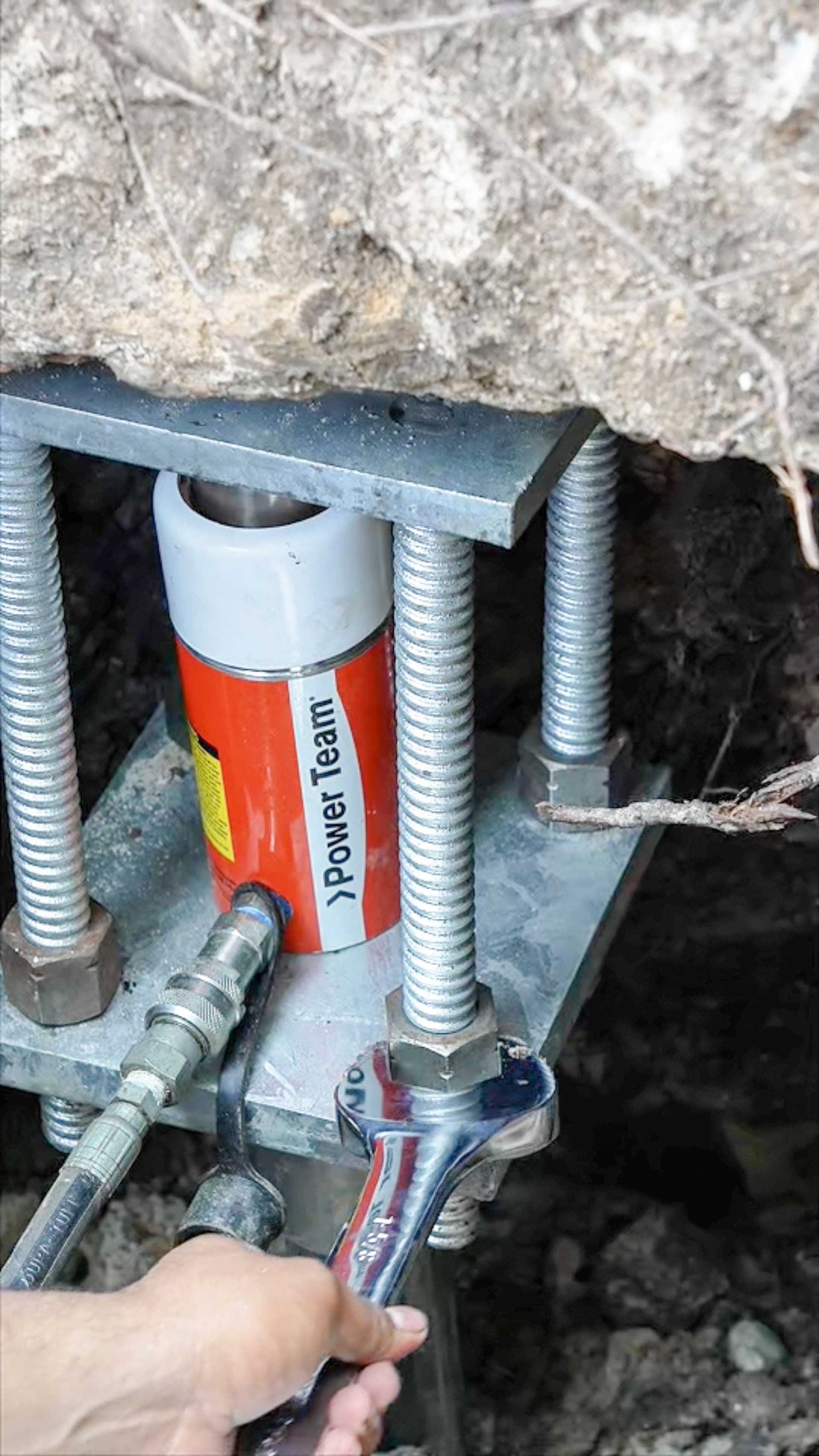 Worker tightening a bolt on a steel foundation bracket with a wrench