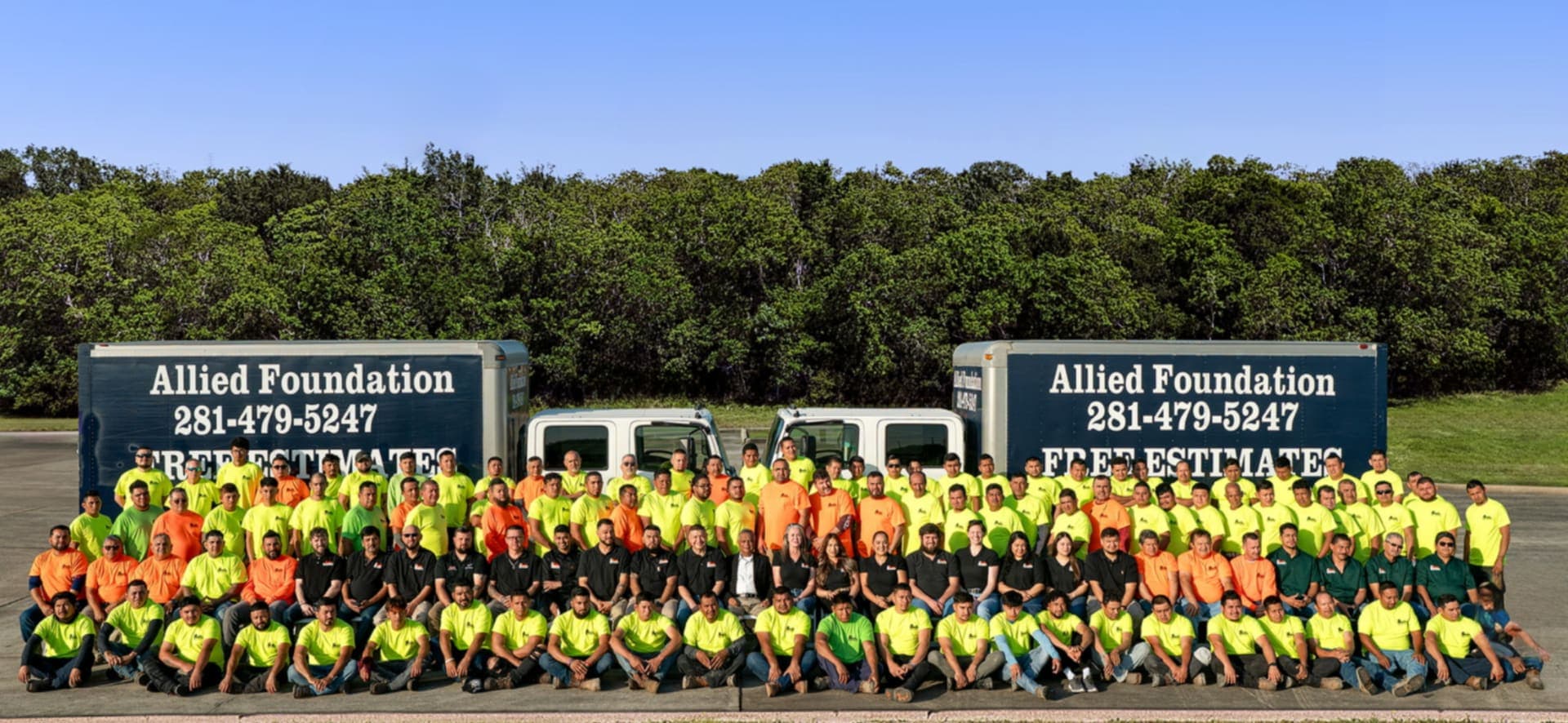 Allied Foundation company photo with the crew in fluorescent shirts in front of two box trucks