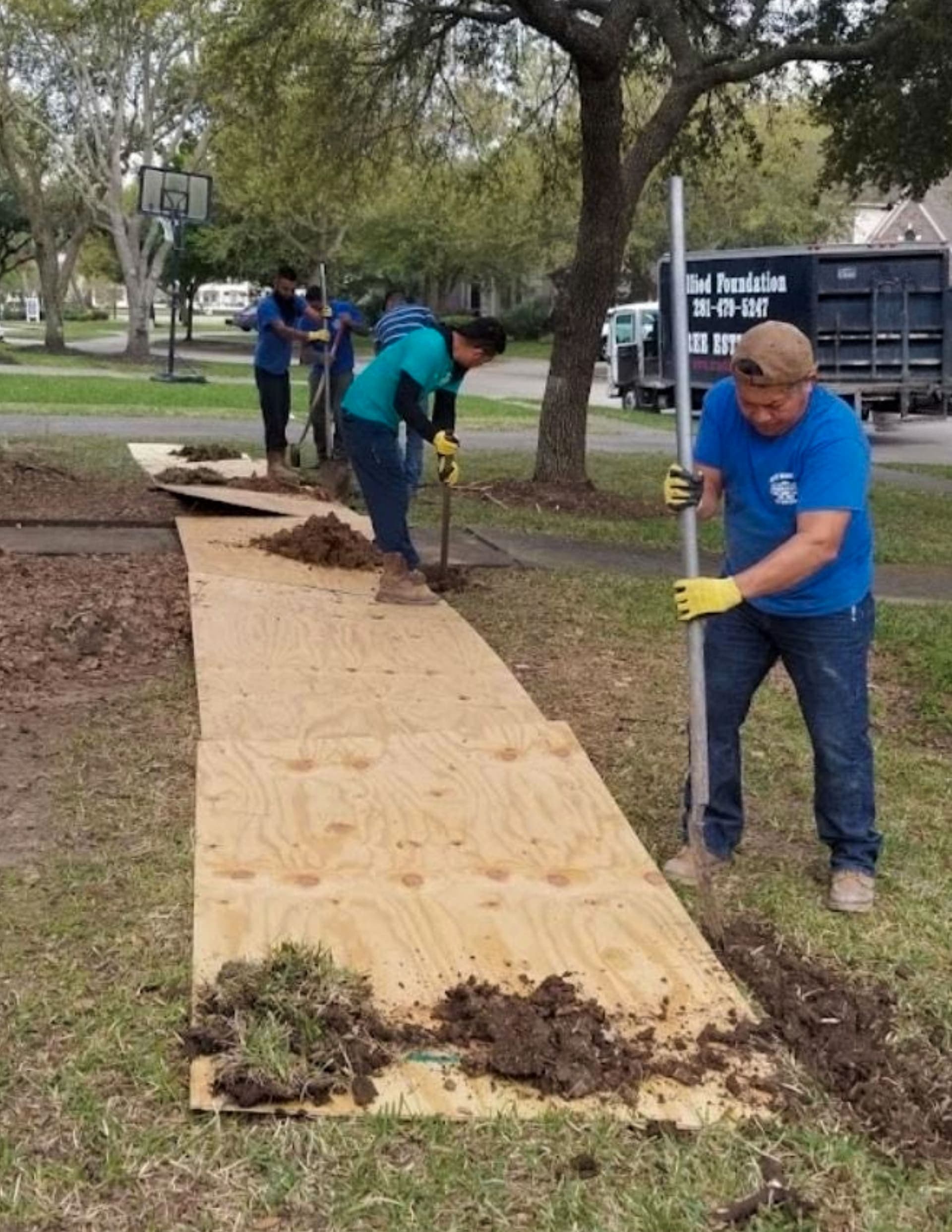 Allied crew digging a root barrier trench with plywood shoring along the side