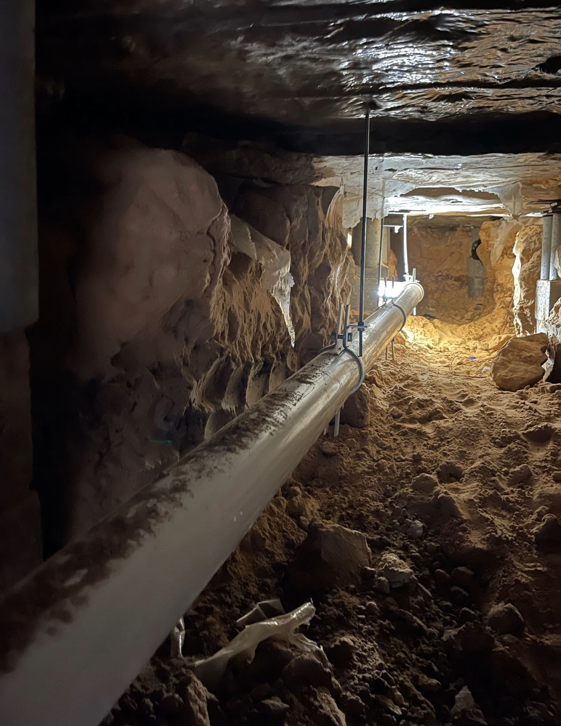 New pipe running the length of an access tunnel with light at the far end
