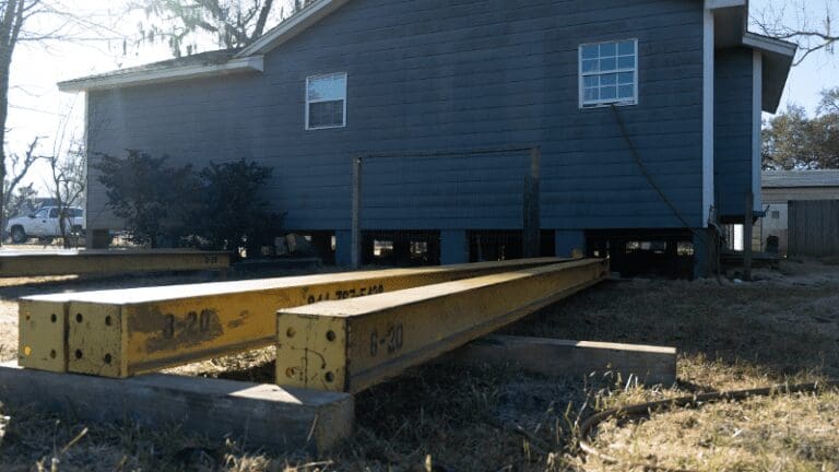 the back of a blue house with two wooden benches in front of it