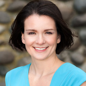 a woman in a blue dress smiling at the camera