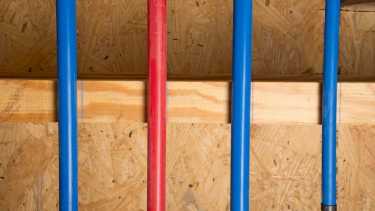 three red and blue baseball bats lined up against a wooden wall