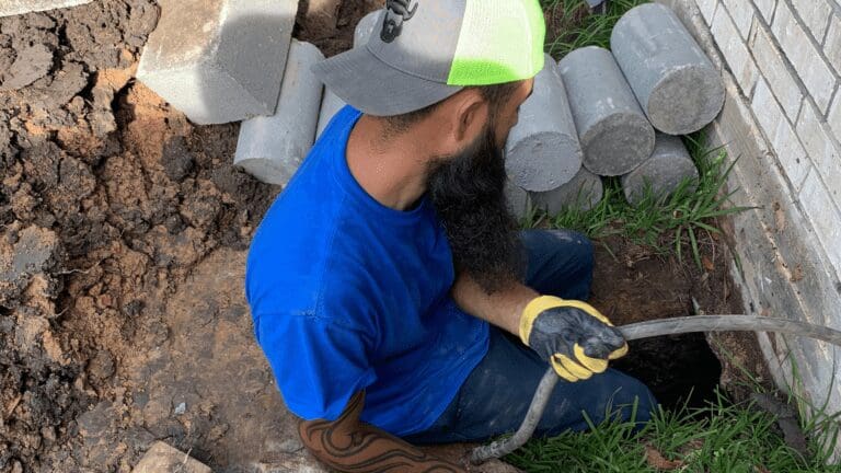 a man in blue shirt and yellow gloves holding a pipe