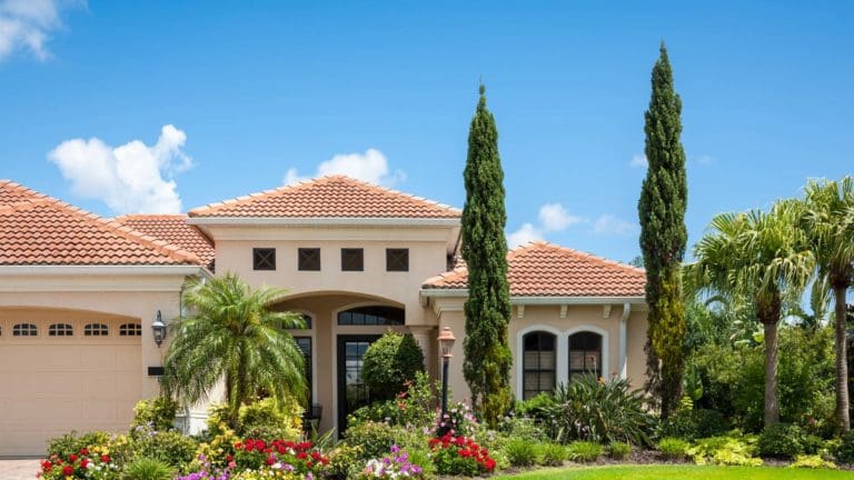 a house with palm trees and flowers in front of it