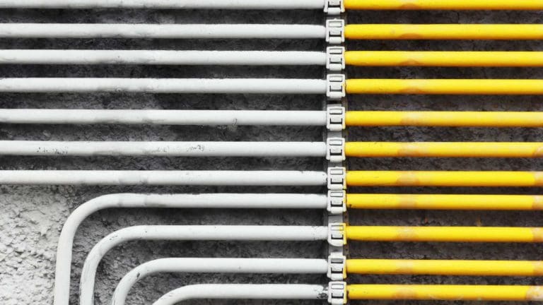yellow and white pipes are lined up against the wall