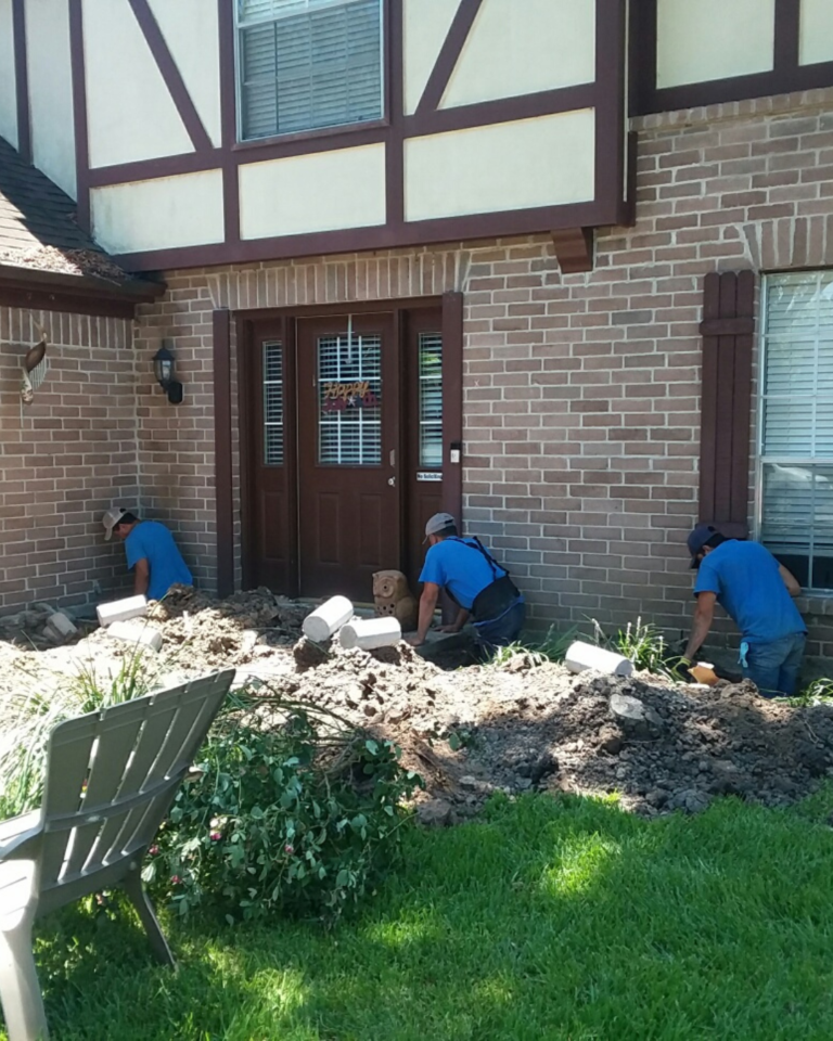 a group of men working on landscaping in front of a house